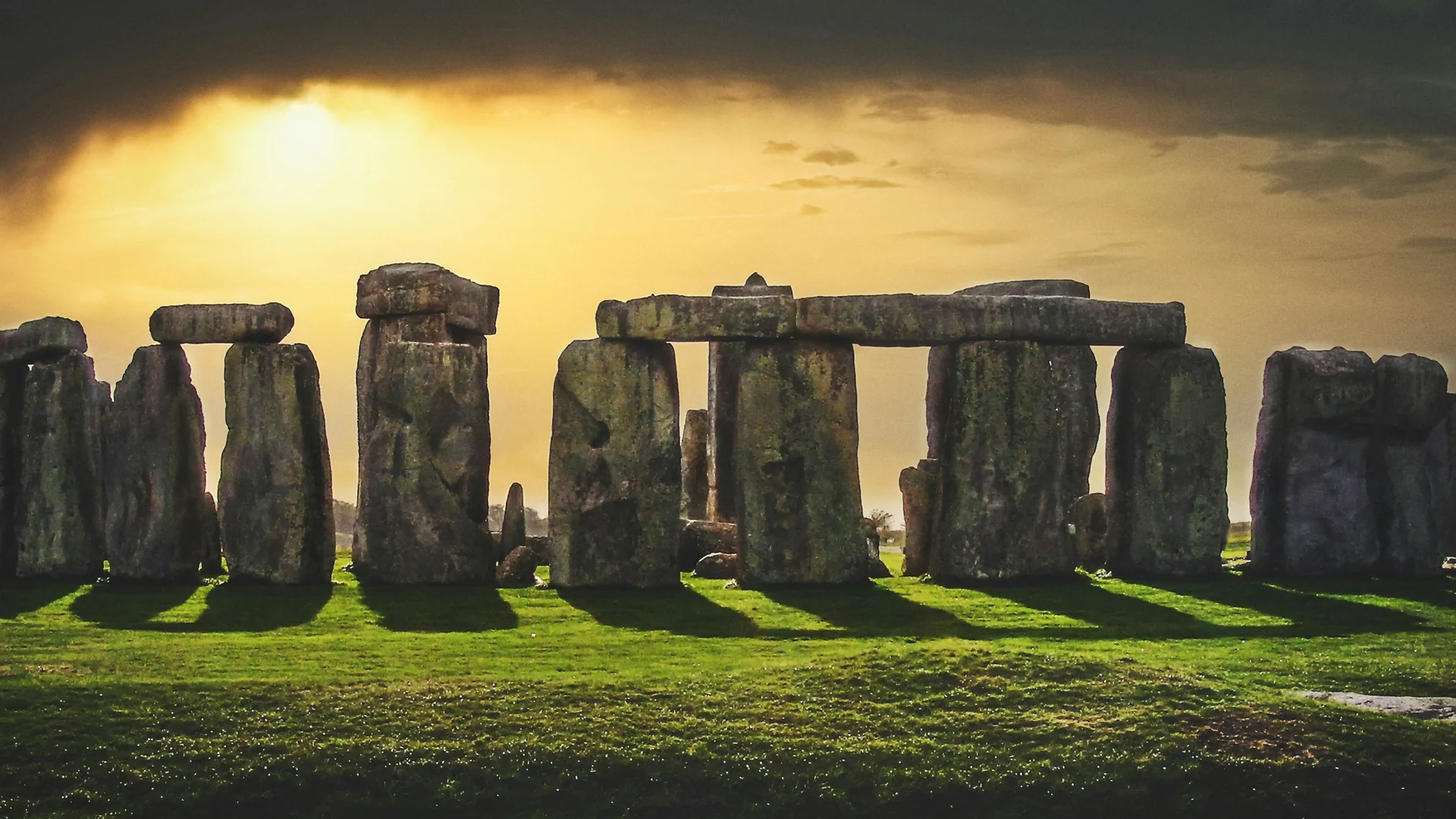 Silueta sarsenového kruhu Stonehenge proti jantarové večerní obloze při západu slunce